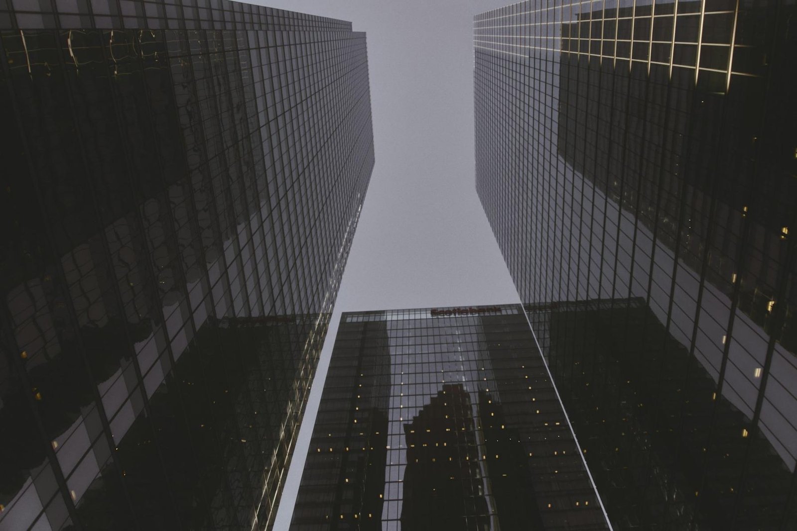 Looking up between dark glass towers in a financial district